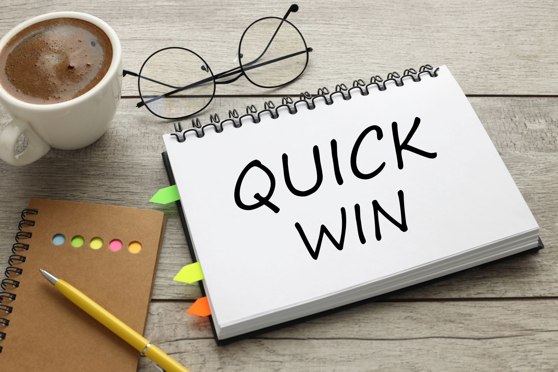 Quick Win Text auf dem Notebook mit Kaffee auf Holztisch